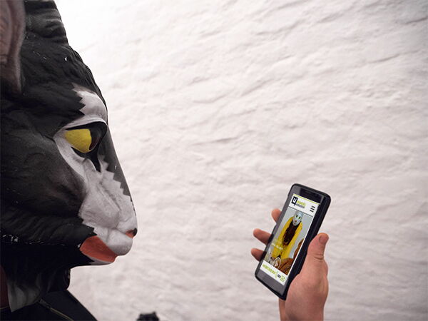 Bild von einem Menschen mit Tiermaske der/die ein Handy in der Hand hält Bild von einem Menschen mit Tiermaske der/die ein Handy in der Hand hält